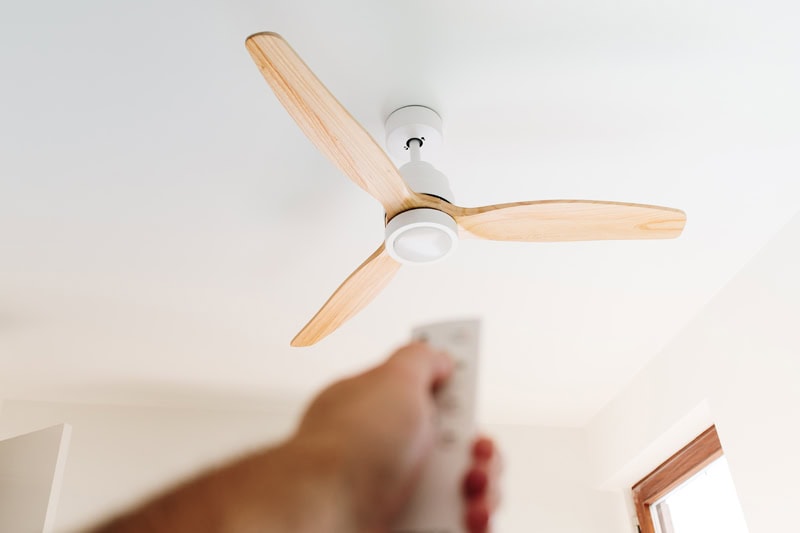 Do I Need an Electrician for Ceiling Fan Installation? A person turning on ceiling fan.